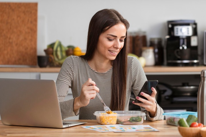 Persona consultando el precio de la luz desde el móvil mientras desayuna en casa.
